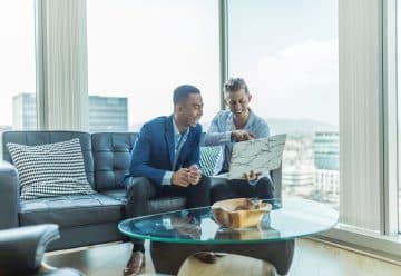 two men in suit sitting on sofa