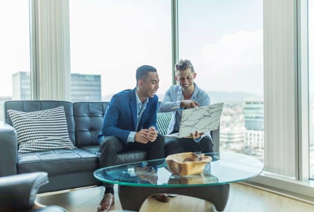two men in suit sitting on sofa